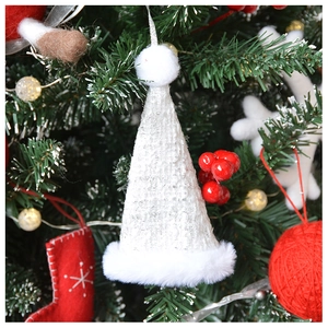 Close-up of white knitted Christmas hat ornament with plush fur trim on festive tree