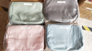 Detailed view of four macaron-colored waterproof makeup bags in pink, grey, green, and blue