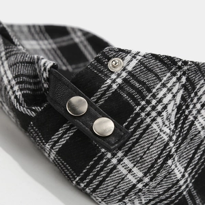 Detail of black and white plaid fabric with leather strap and silver metal buttons