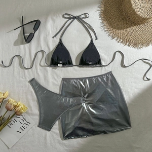 Flat lay of metallic silver and black three-piece bikini set with vacation accessories