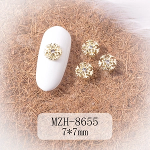 Macro view of 7x7mm gold snowflake nail charms with center crystal for DIY manicure