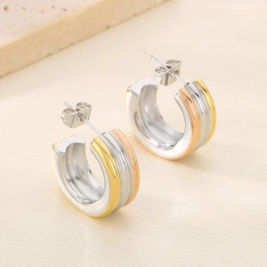 Détail de boucles d'oreilles en C avec une finition tricolore or, argent et rose