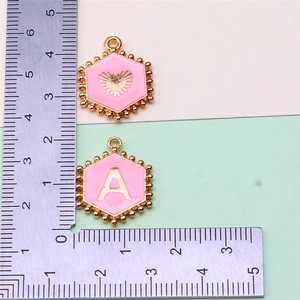 Detailed view of pink enamel alphabet pendants with ruler showing 1.5cm size