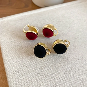Detail of vintage gold hoop earrings with black and wine red velvet inlay on a textured board
