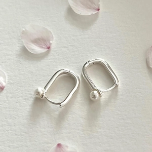Elegant 925 sterling silver U-shaped hoop earrings with pearls on textured paper background
