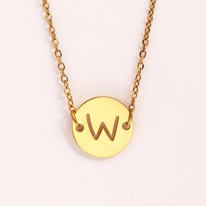 Gros plan détaillé d'un collier doré avec un pendentif pièce ajouré de la lettre W ciselée