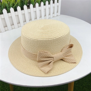 Detail of summer straw hat with a striped khaki ribbon and a decorative bow tie