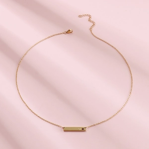Detailed view of a gold horizontal bar necklace featuring a tiny heart and birthstone inlay