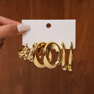 Detail of six-piece golden geometric stud earring set held on white card display