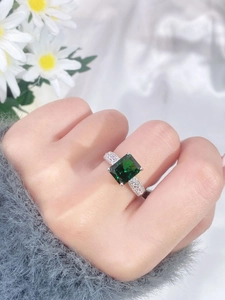 Close-up of luxury rectangular emerald cut green gemstone ring on a woman's finger