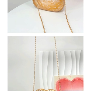 Detailed close-up of amber stone pattern acrylic heart-shaped evening bag with gold chain
