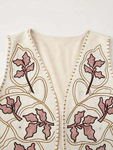 Detail of beige sleeveless vest featuring pink leaf embroidery and golden edge stitching