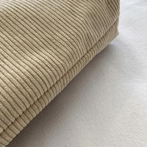 Macro shot of beige corduroy fabric texture showing vertical stripes and soft velvet finish