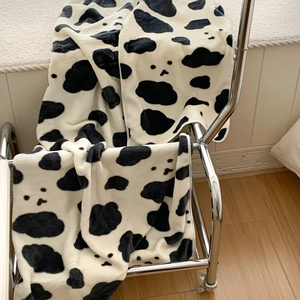 Thick black and white cow print coral fleece towel draped over a metal chair frame