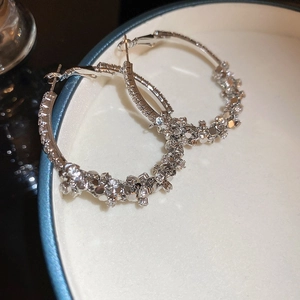 Detailed close-up of silver hoop earrings paved with sparkling zircon stones in a box