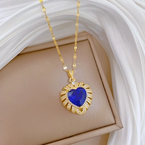 Macro detail of luxury gold heart pendant with deep blue gemstone and white zircon pavé
