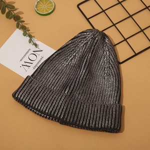 Close-up of metallic dark grey knit beanie with silver lurex on stylized yellow background