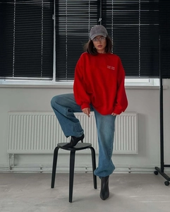 Detail of red oversized crewneck sweatshirt with white letter embroidery on the chest