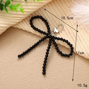 Detail view of a handcrafted black beaded bow keychain with exact dimensions and weight