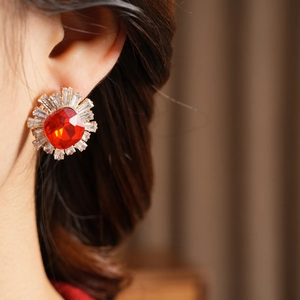 Macro detail of vintage sunburst stud earrings with red main stone and baguette zircons