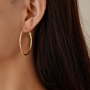Close-up of elegant gold geometric circular hoop earrings worn by a model