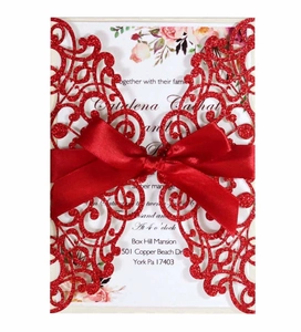 Detailed laser-cut red wedding invitation with elegant satin bow and floral inner page