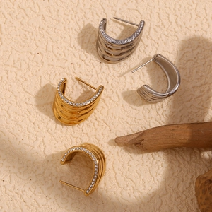 Detail of layered gold and silver wave earrings with sparkling zircon micro-inlay