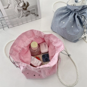 Detail view of pink and blue drawstring bucket bags with star studs and pearl chains