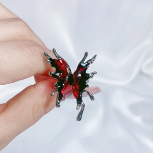 Detail of red enamel butterfly ring featuring liquid metal style silver finish