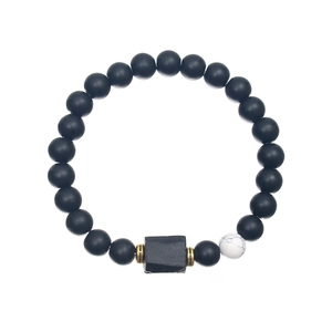 Detailed close-up of beaded bracelet with black stones and a white marble accent bead