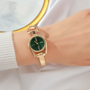 Close-up of vintage golden bangle watch featuring a green dial and Roman numerals
