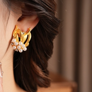 Close-up of vintage pearl and zircon gold earrings on model highlighting the leaf design