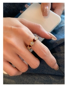 Detail of gold-plated open ring featuring red and white enamel heart shapes on hand