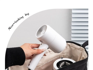 Hand putting compact white hair dryer into a portable black travel storage bag