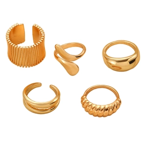 Nahaufnahme eines fünfteiligen Goldring-Sets mit Lavatropfen und geometrischen Hohlmustern