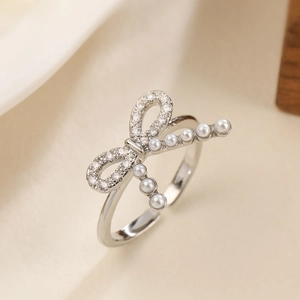 Macro shot of silver bow ring featuring sparkling zircons and delicate white pearls
