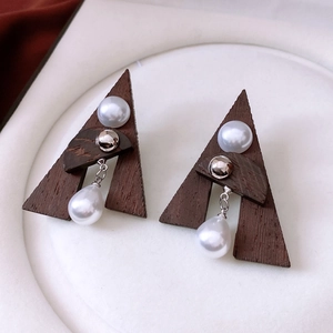Macro shot of geometric wooden triangle earrings with pearls and silver metal accents
