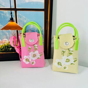 Close-up of floral knit phone bags with bright green resin handles and metal snap closure