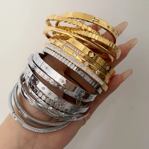 Detail of layered gold and silver stainless steel bangles with star and sun engravings