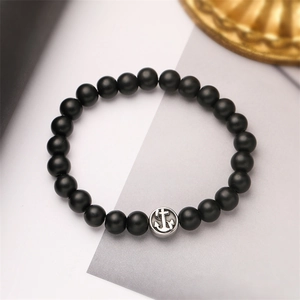 Dettaglio di perle occhio di tigre nero opaco con ciondolo ancora in argento su bracciale