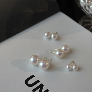 Detailed close-up of four pairs of gradient-sized pearl stud earrings on white card