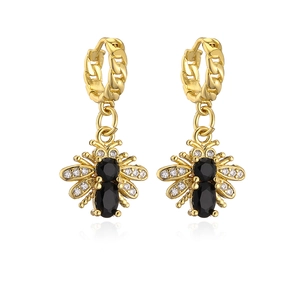 Macro detail of gold plated bee earrings with black oval gems and sparkling crystal wings
