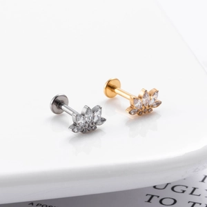 Close-up of gold and silver lotus stud earrings with zircons on a book page