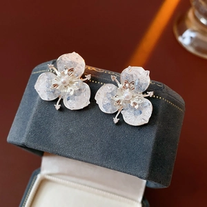 Macro detail of silver flower earrings with white pearl and crystal petals on velvet