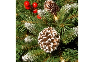 Close-up of artificial pine needles with snow effect, pine cones, red berries and LED lights