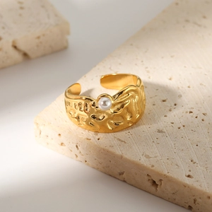 Adjustable 18k gold stainless steel lava ring with a white pearl on travertine background