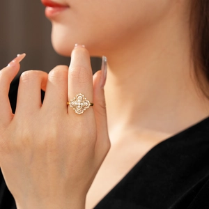 Gros plan d'une bague trèfle dorée ornée de perles élégantes et de diamants scintillants