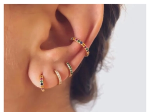 Close-up of rainbow zirconia hoop earrings in rose gold stacked on a model's ear