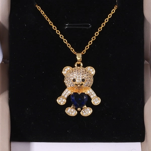 Golden necklace with a micro-paved bear pendant holding a blue heart-shaped stone