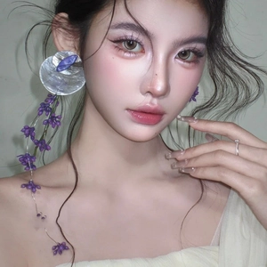 Elegant silver asymmetrical earrings with purple flower tassels and long fringe on a model